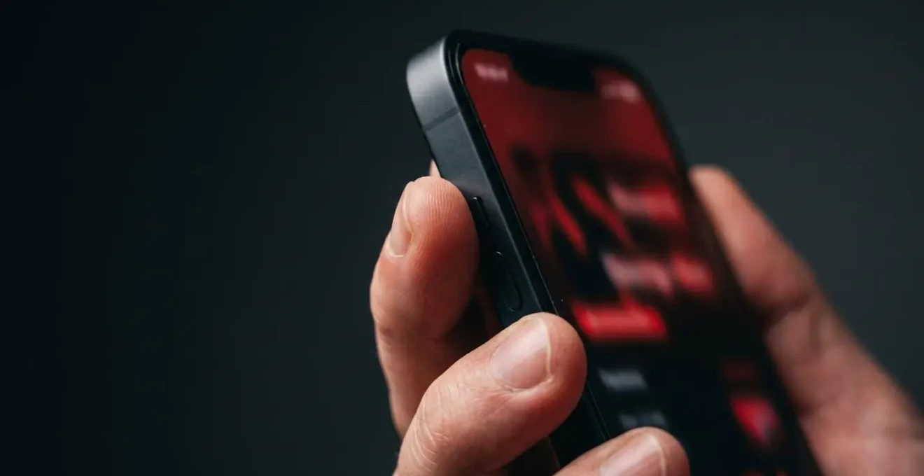 Gros plan sur une main tenant un smartphone affichant une notification d'alerte bancaire avec fond rouge