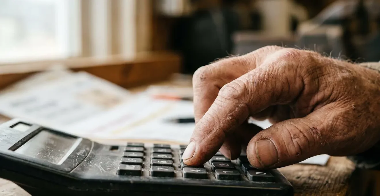 Gros plan sur des mains d'artisan utilisant une calculatrice avec documents fiscaux
